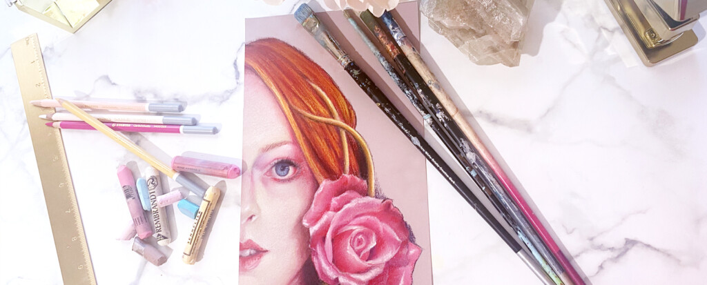 Art supplies including colored markers, paintbrushes, and a ruler scattered around an unfinished illustration of a woman with red hair and a whimsical pink rose on a marble surface.